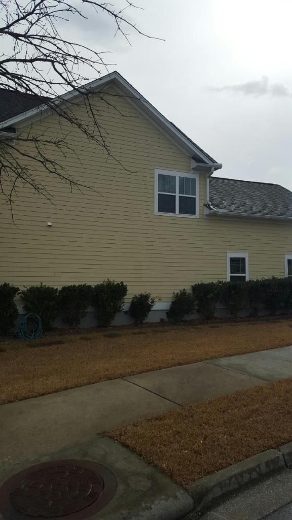 A house with a lot of windows and a roof is sitting on the side of the road.