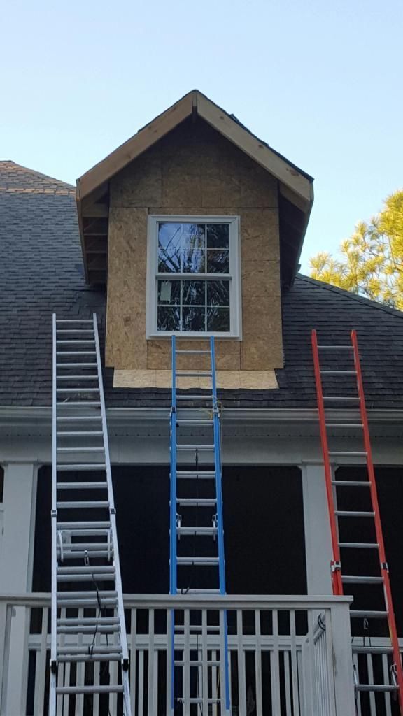 Two ladders are sitting on top of a house under construction