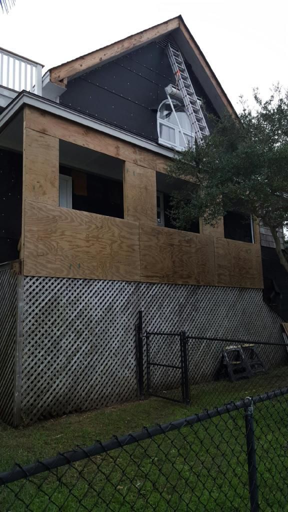 A house is being remodeled with a chain link fence in front of it.