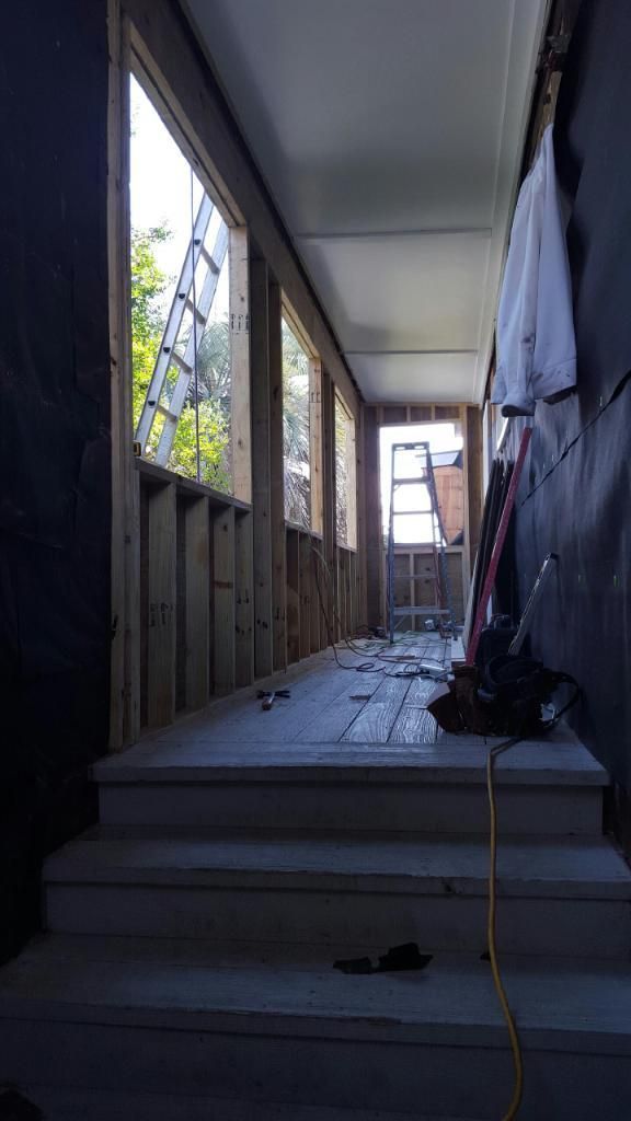 A long hallway with stairs and a ladder in a building under construction.