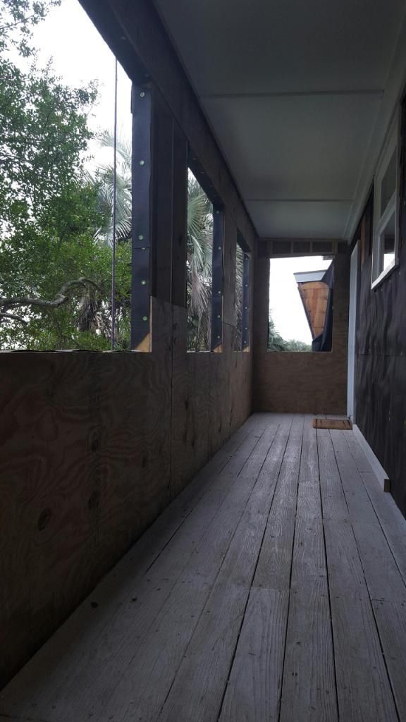 A long hallway with a wooden floor and a lot of windows