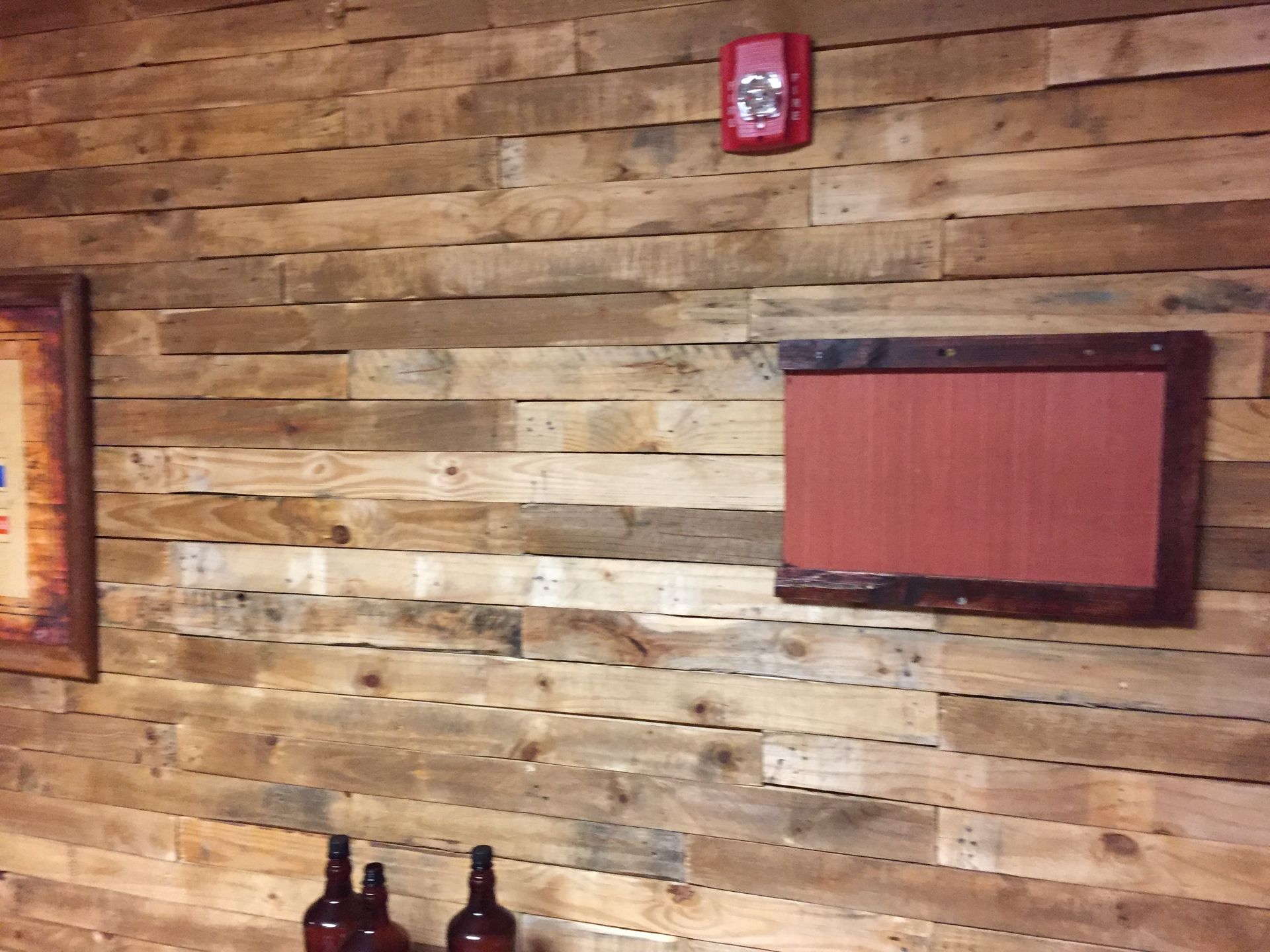 A wooden wall with bottles and a sign on it