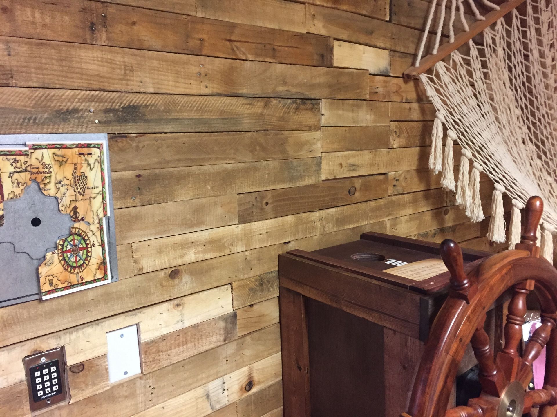 A wooden room with a steering wheel and a map on the wall.
