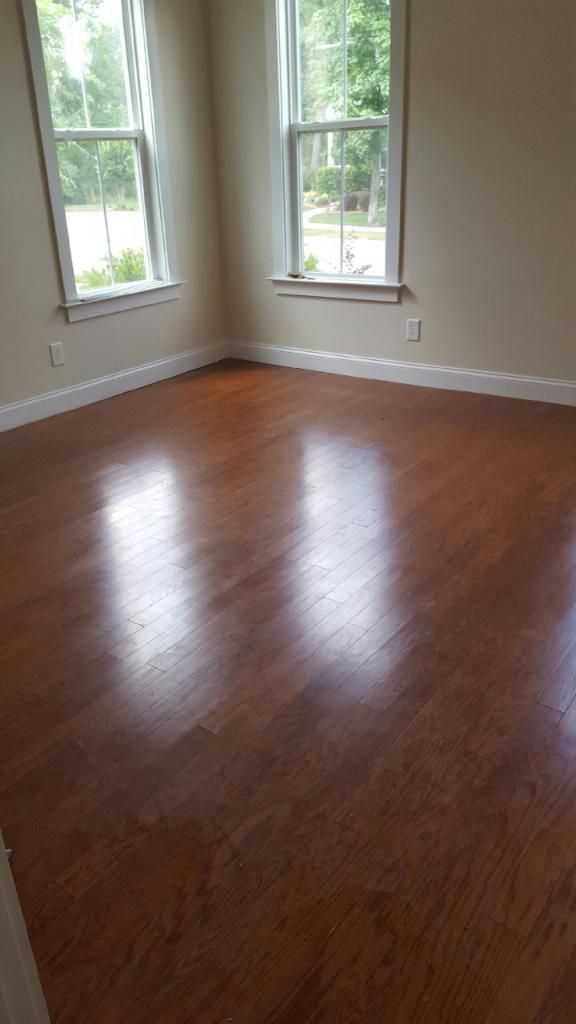 An empty room with hardwood floors and two windows
