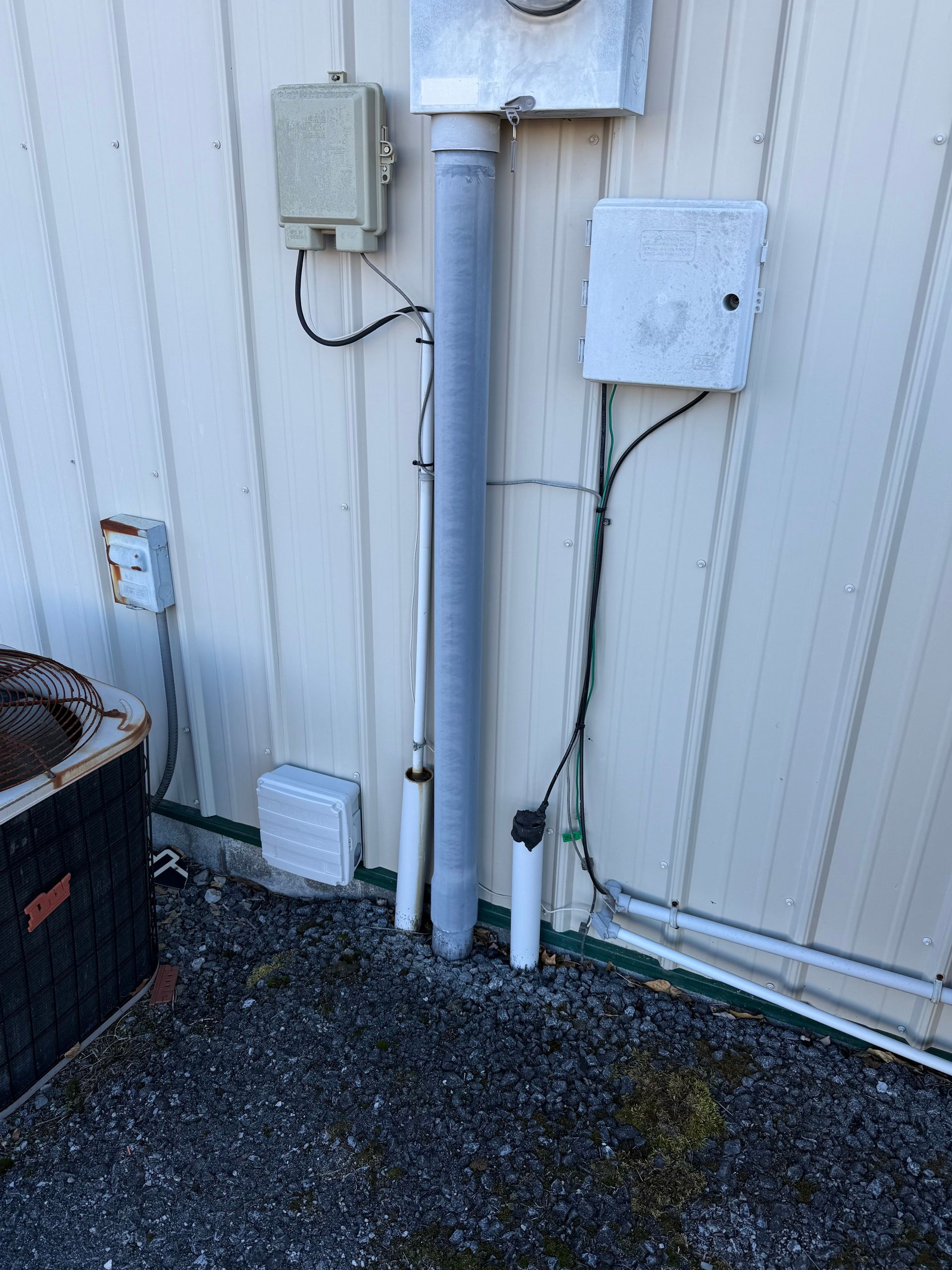 Exterior wall with various utility boxes and conduit running down.