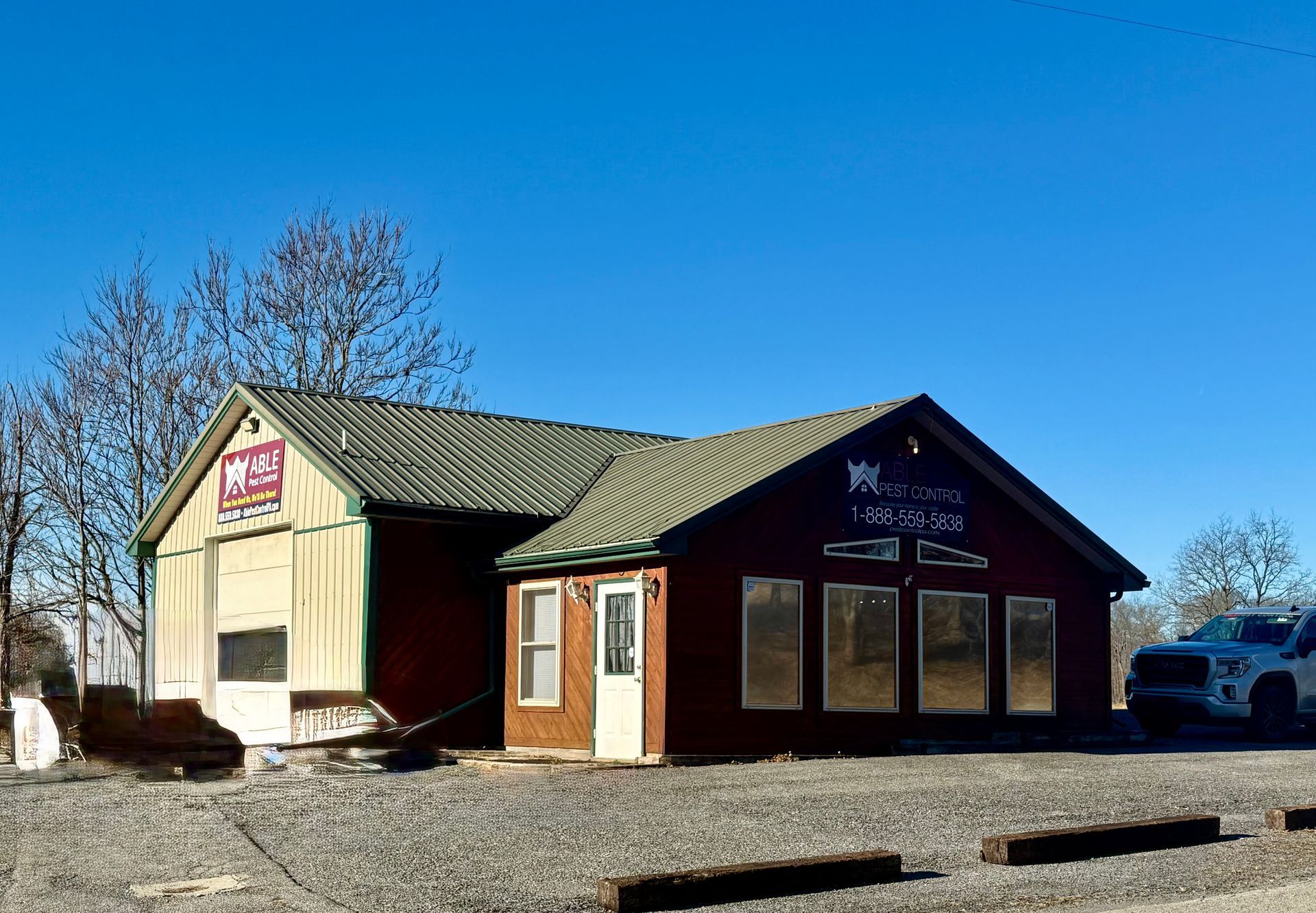 A small, weathered building with two sections: a light beige and a red, against a blue sky.