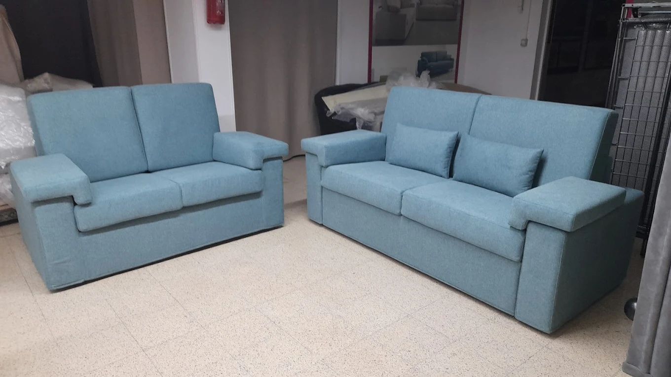 Divano azzurro composto da due pezzi su pavimento marrone chiaro.