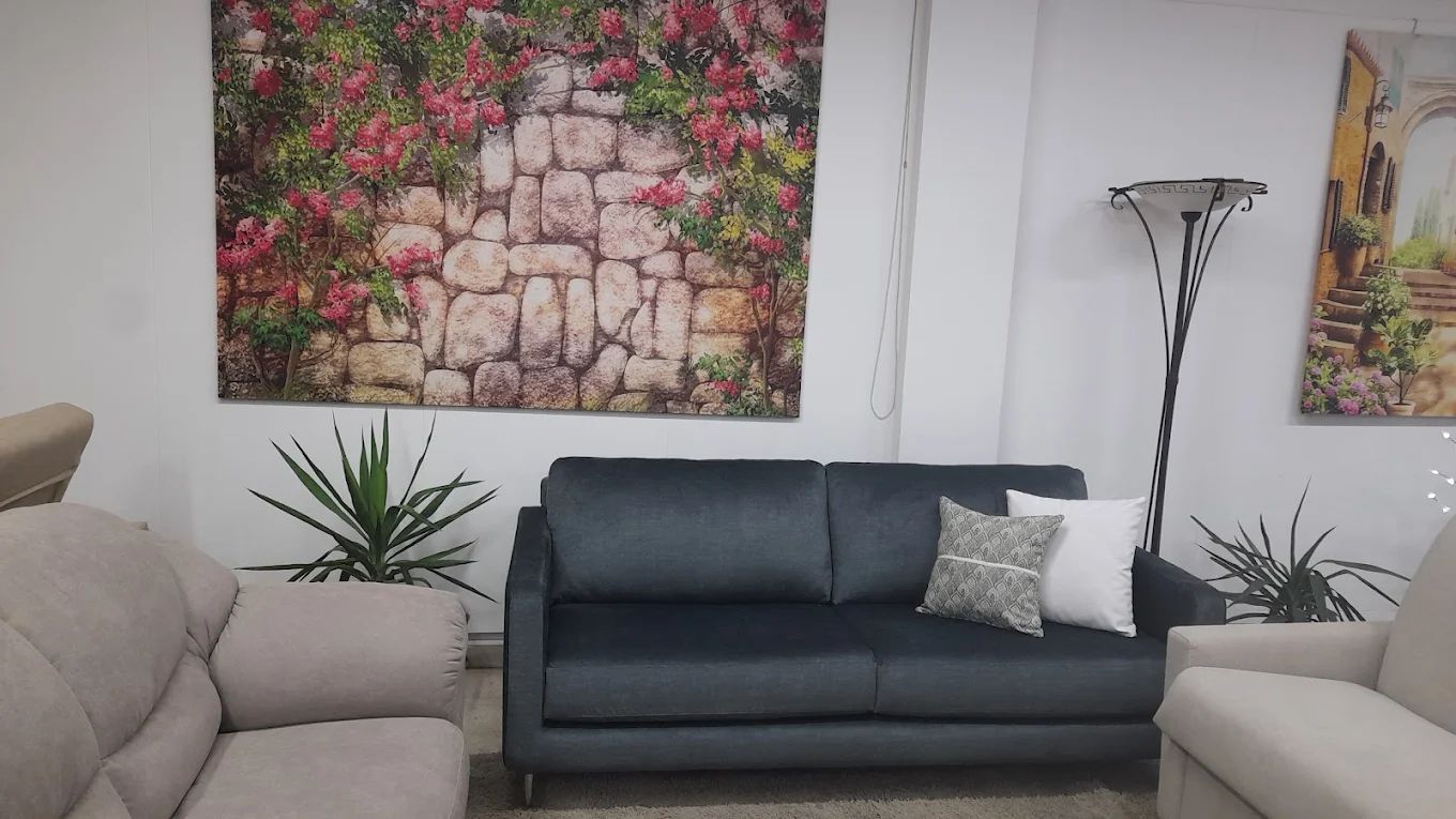 Soggiorno con divano blu scuro, divani bianchi, opere d'arte e piante.