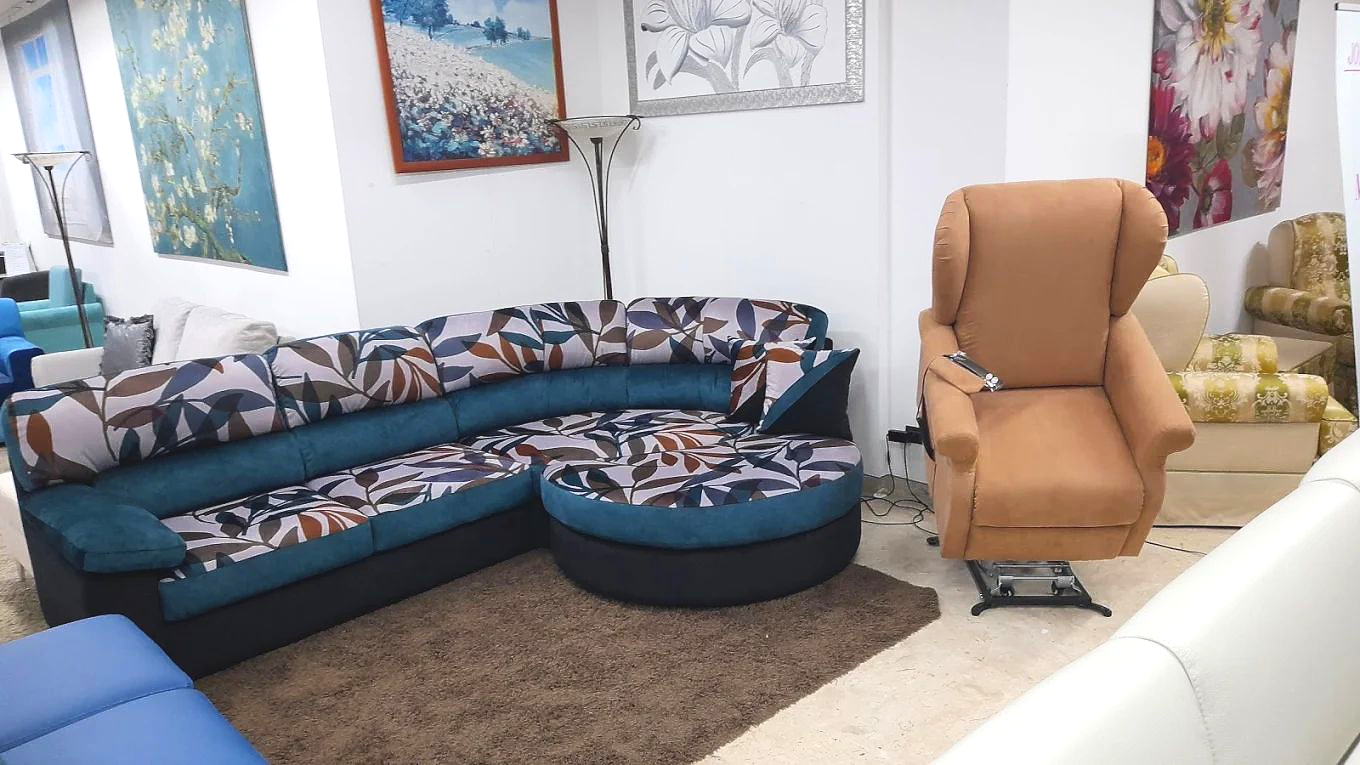 Interno di un negozio di mobili con un divano componibile con cuscini fantasia e una poltrona reclinabile marrone su un tappeto.