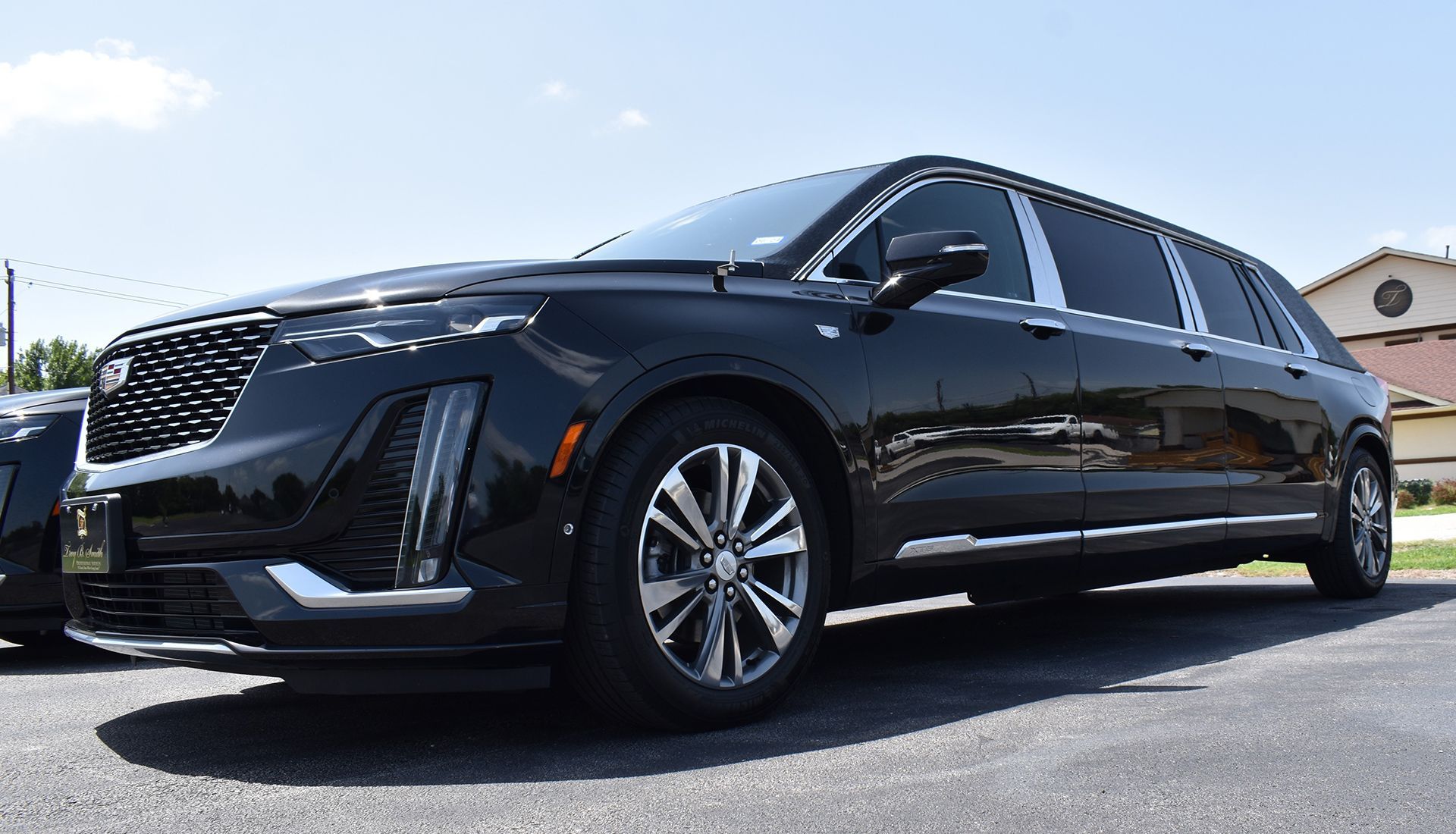 Black Cadillac XT6 limousine parked outside on a sunny day.