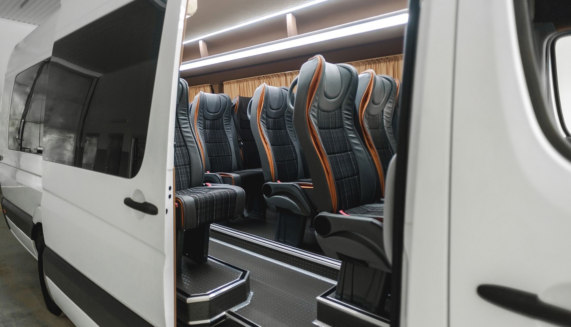 Interior view of a white passenger van with black and orange seats.
