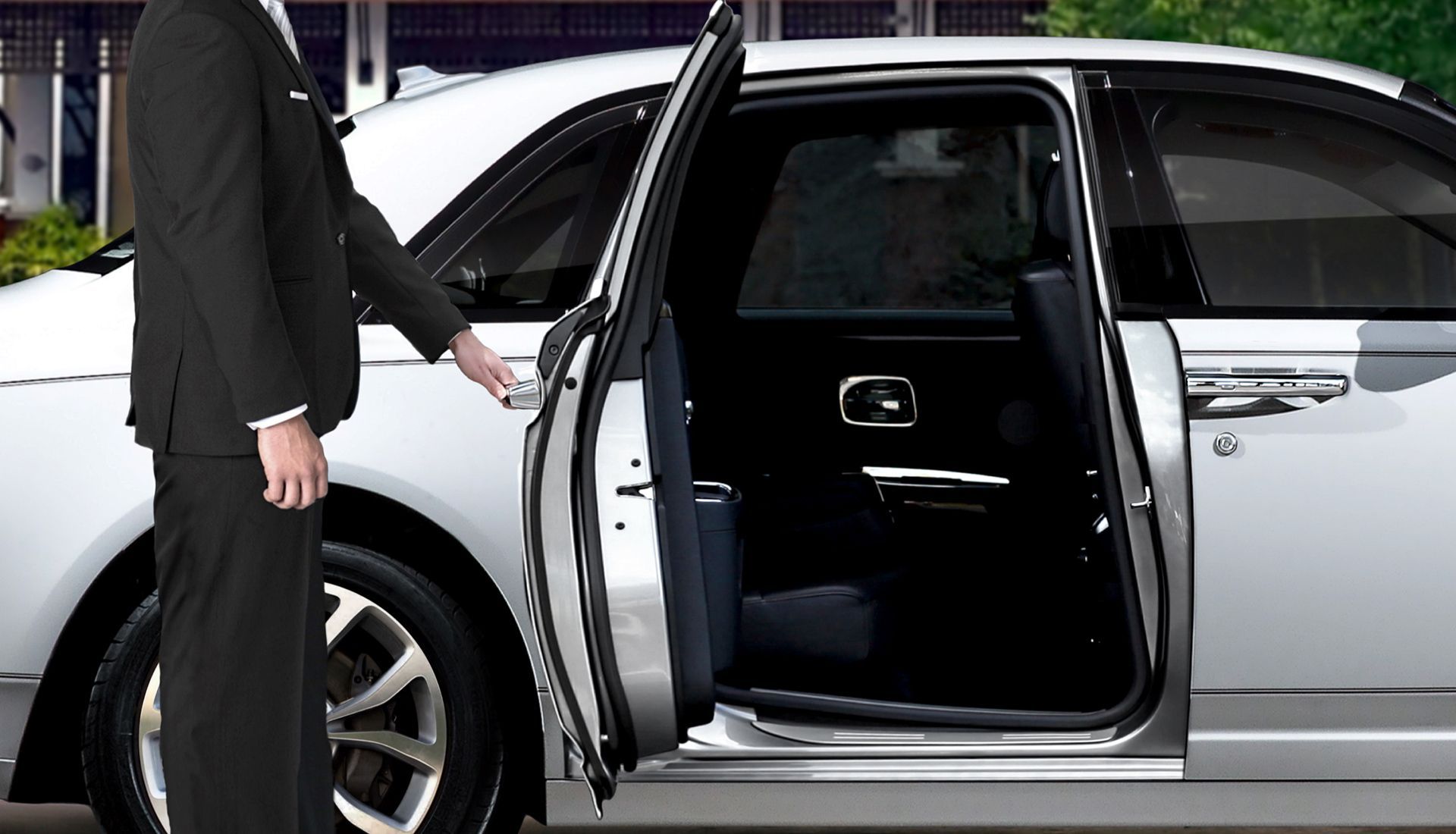 Butler opening the door of a silver luxury car. The interior is black.