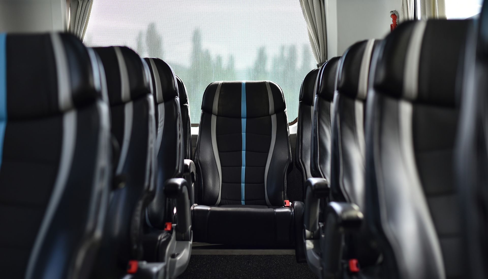 Rows of black bus seats with blue and white accents, viewed from the aisle looking towards the back of the bus.