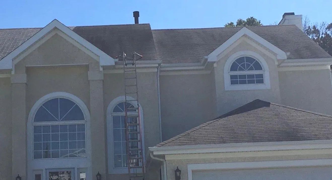 A two-story house with a dirty roof, ladder, and arched windows.