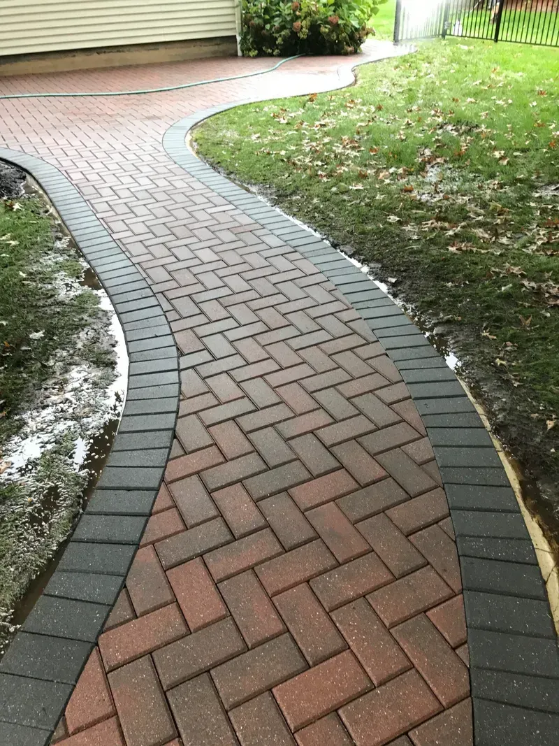 Two-story brick house with a tan garage door, green lawn, and blue sky.