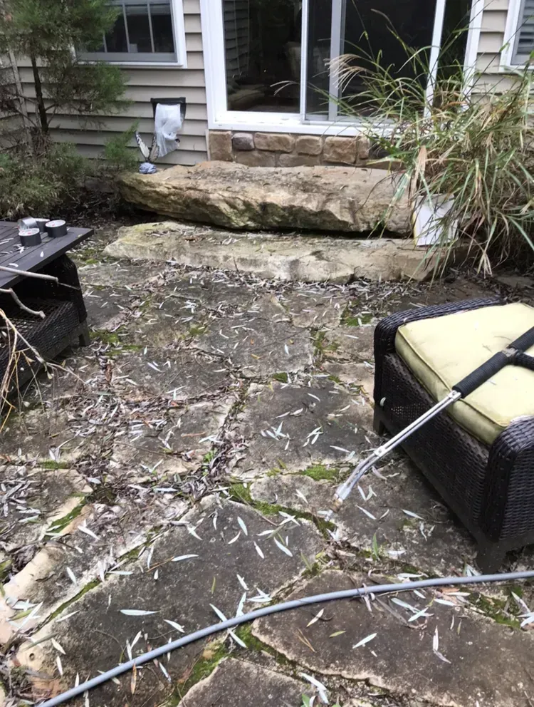 Patio with stone pavers, two chairs, and a sliding glass door. A pressure washer is visible.