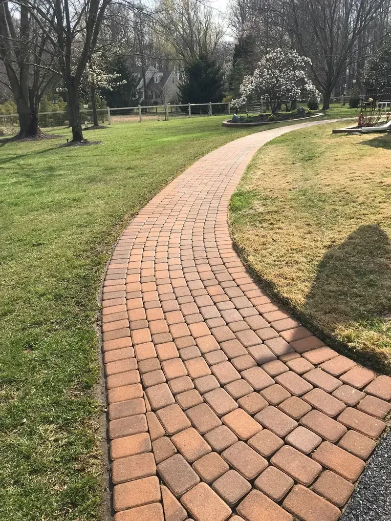 Brick pathway curves through a grassy yard.