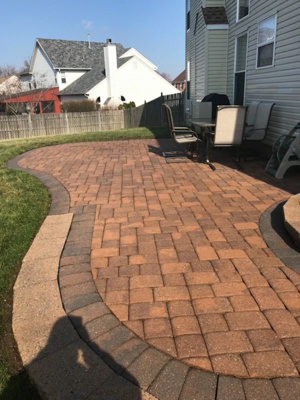 Two-story brick house with a tan garage door, green lawn, and blue sky.