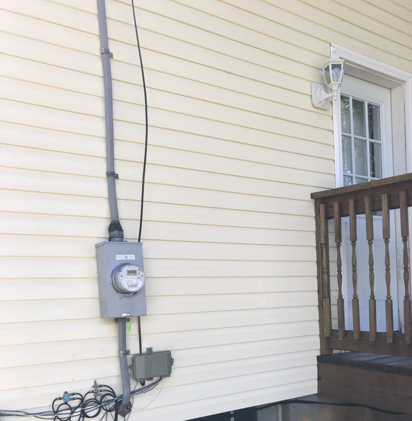 Two-story brick house with a tan garage door, green lawn, and blue sky.