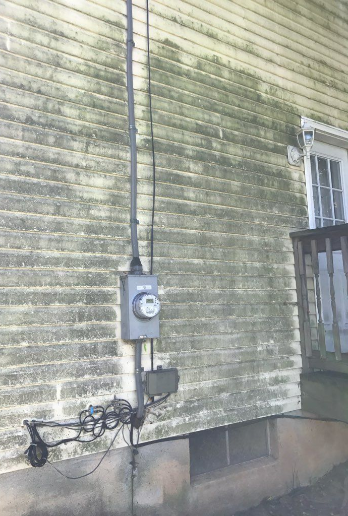 Two-story brick and siding house with a dark roof and a two-car garage, on a green lawn.