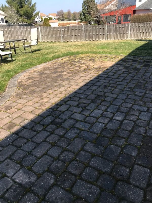Brick walkway with scattered brown leaves, bordered by green grass.