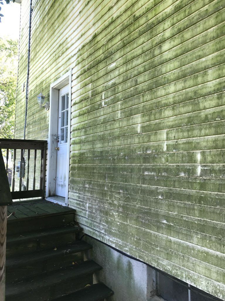 White wooden siding with visible weathering and green moss.