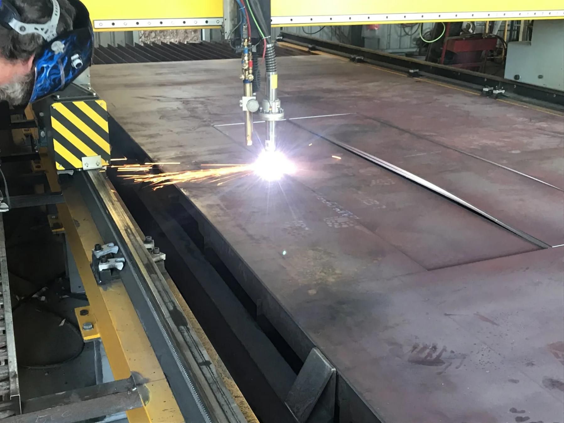A Man Is Cutting A Piece Of Metal With A Machine — HardRok Engineering Pty Ltd In Mount Isa, QLD
