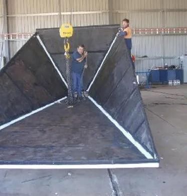 Two Men Are Working On A Large Piece Of Metal In A Warehouse — HardRok Engineering Pty Ltd In Mount Isa, QLD