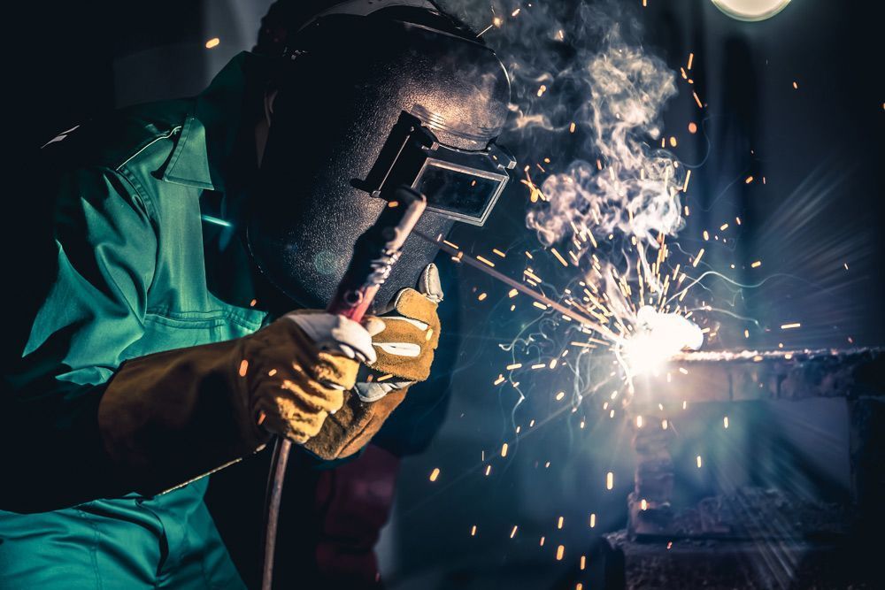 A Man Wearing A Welding Mask Is Welding A Piece Of Metal — HardRok Engineering Pty Ltd In Mount Isa, QLD