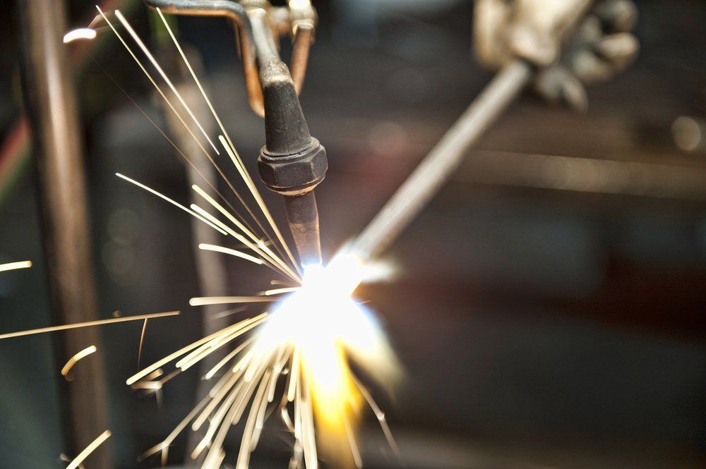 A Person Is Welding A Piece Of Metal With Sparks Coming Out Of It — HardRok Engineering Pty Ltd In Mount Isa, QLD