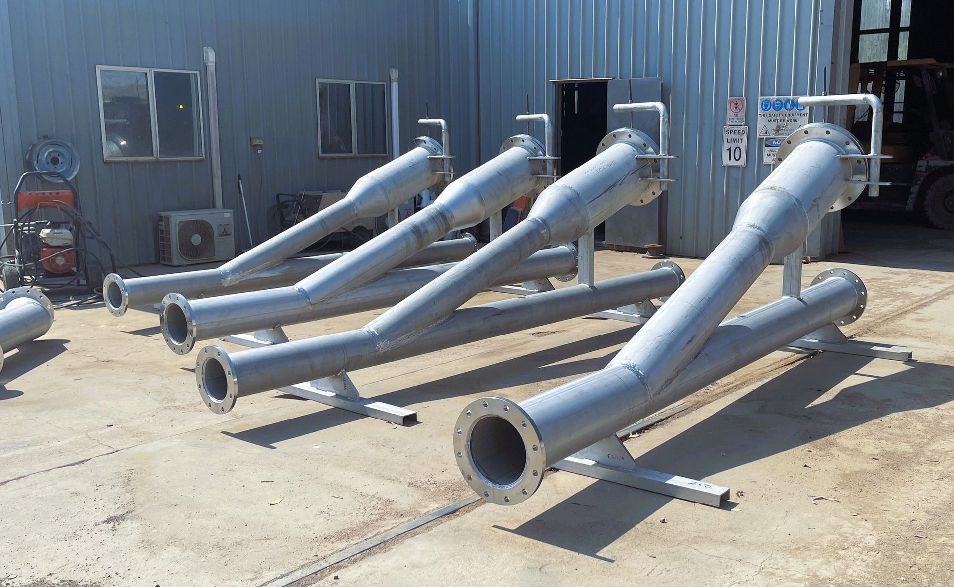 A Bunch Of Metal Pipes Are Sitting Outside Of A Building — HardRok Engineering Pty Ltd In Mount Isa, QLD