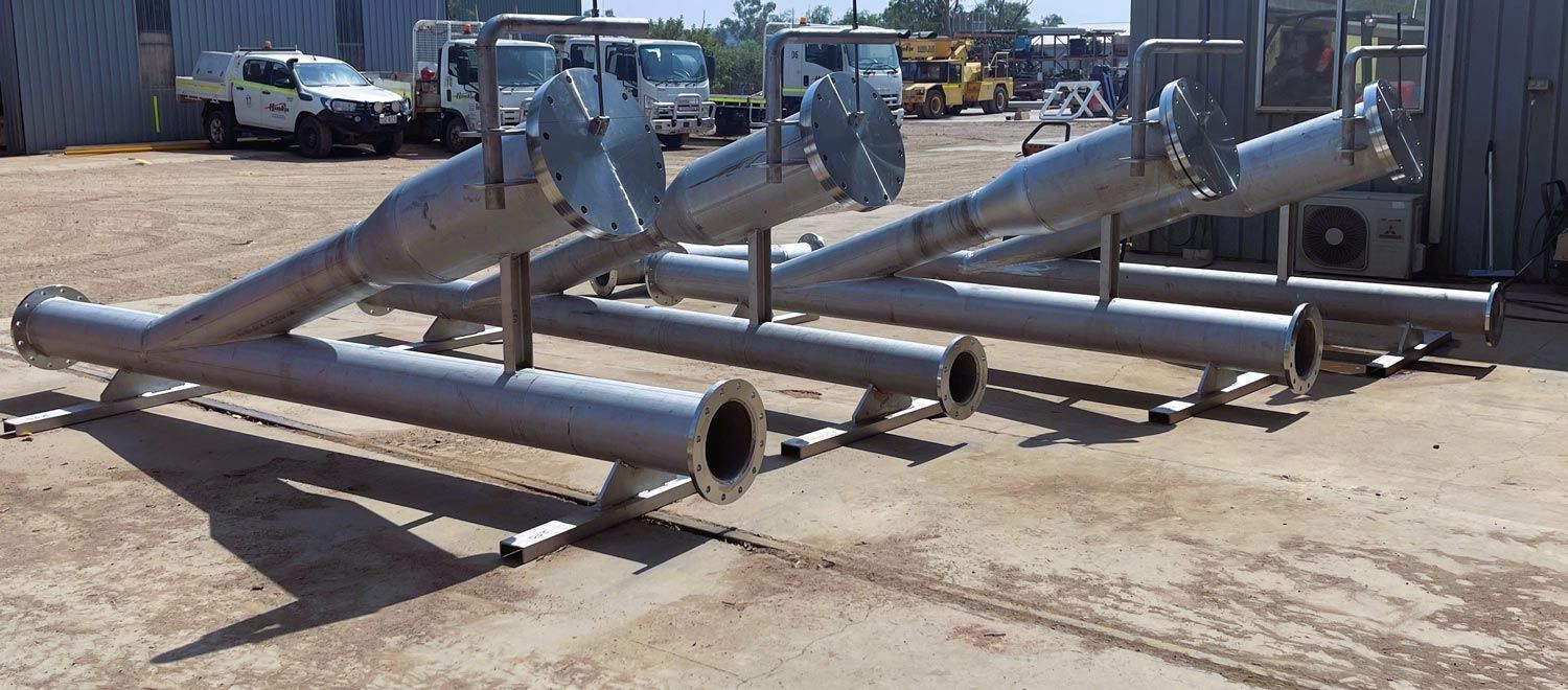 A Bunch Of Metal Pipes Are Sitting On The Ground — HardRok Engineering Pty Ltd In Mount Isa, QLD