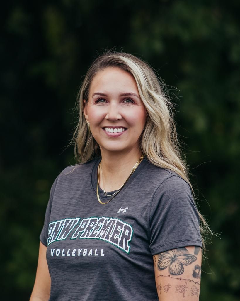 Smiling person in a gray Vanderbilt volleyball T-shirt standing outdoors against a dark green background