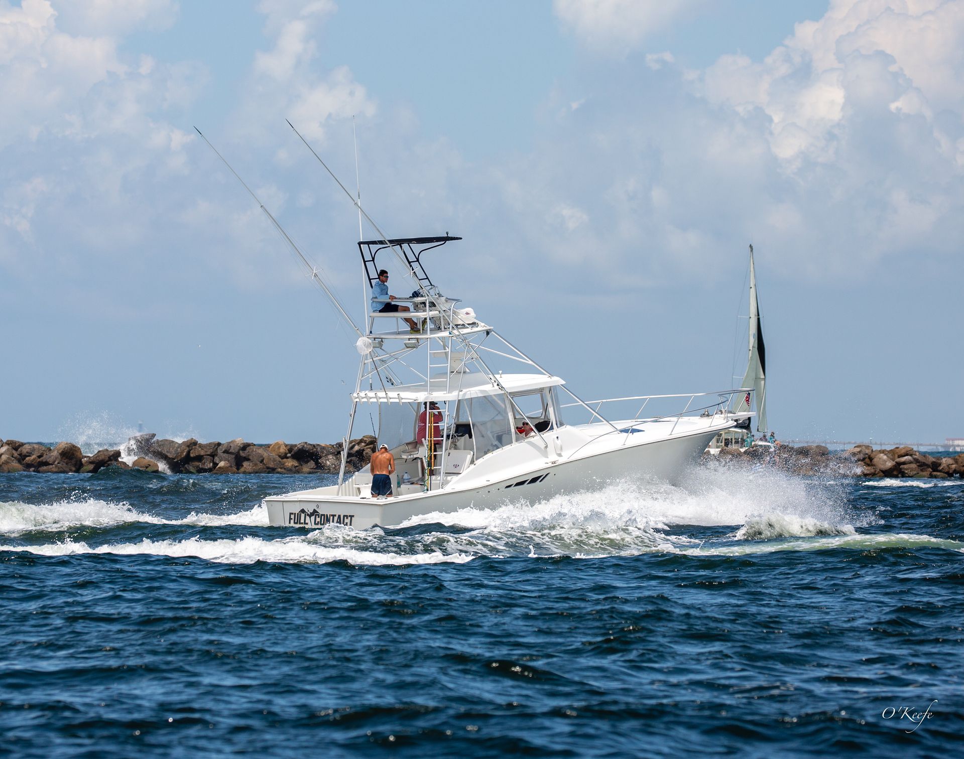 Interior view of a boat's helm, with steering wheel, navigation screen, and clear enclosure with water view.