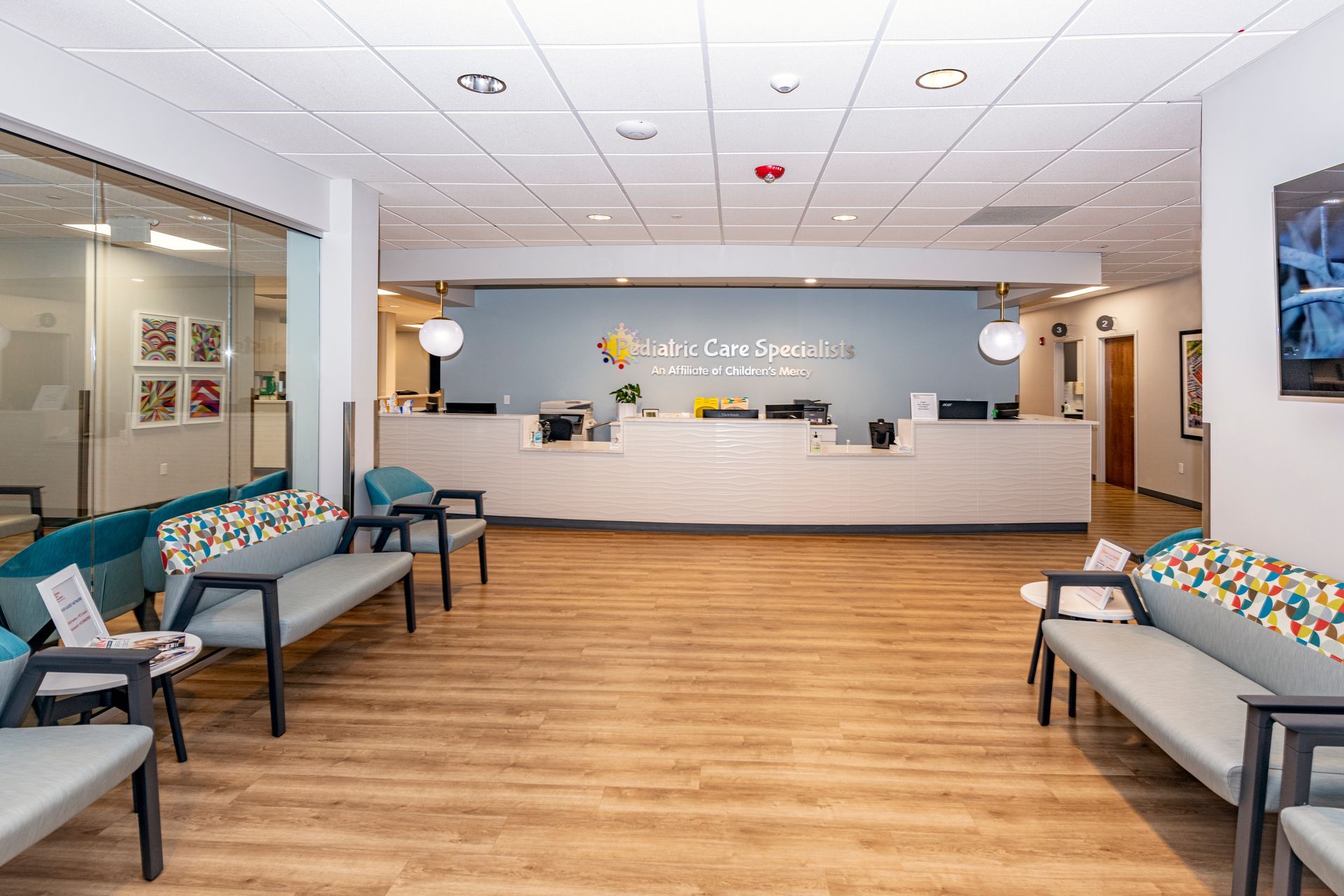 Pediatric Care Specialists waiting room with a couch , chairs , and a counter.