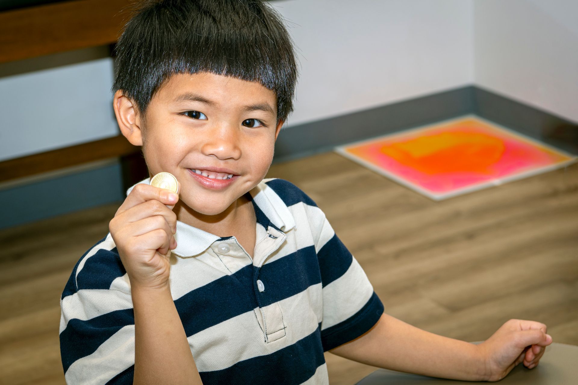 A young boy in a striped shirt is holding a small object in his hand.