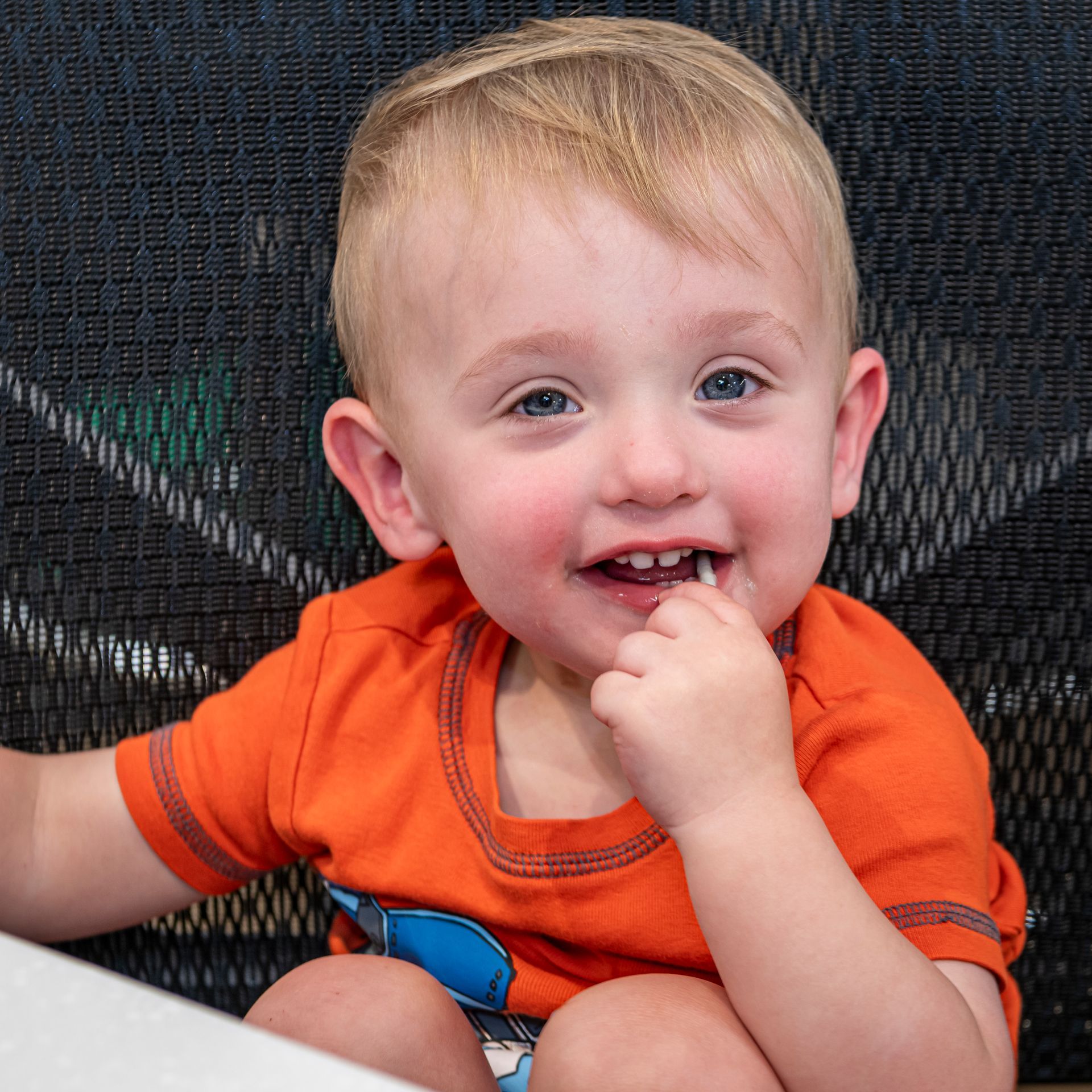 A little boy wearing an orange shirt with a shark on it