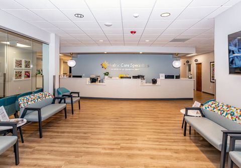 Pediatric Care Specialists waiting room with a couch , chairs , and a counter.