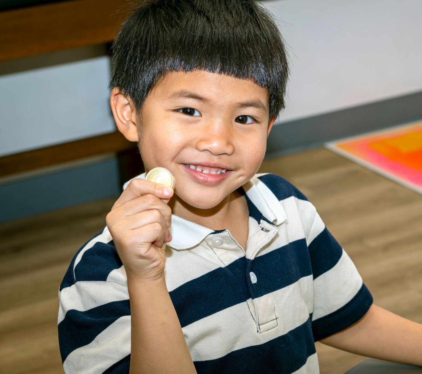 Little boy smiling while he holds up a chocolate wrapped as a gold coin