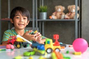 A young boy is sitting at a table playing with toys.