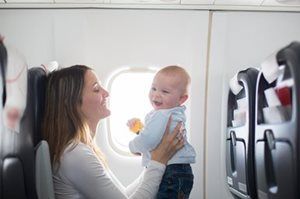 A woman is holding a baby on an airplane.