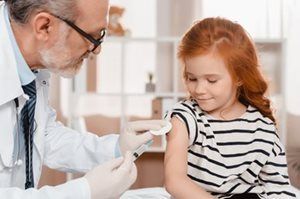 A little girl is getting an injection from a doctor.