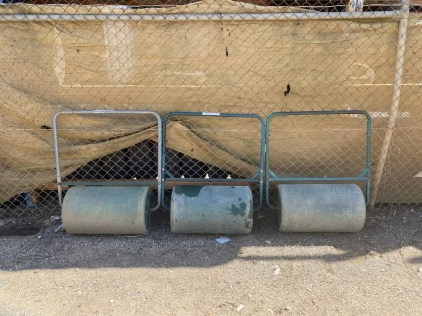 Three Lawn Rollers Are Sitting on the Ground in Front of a Chain Link Fence — Hamblin Hire in Albury, NSW