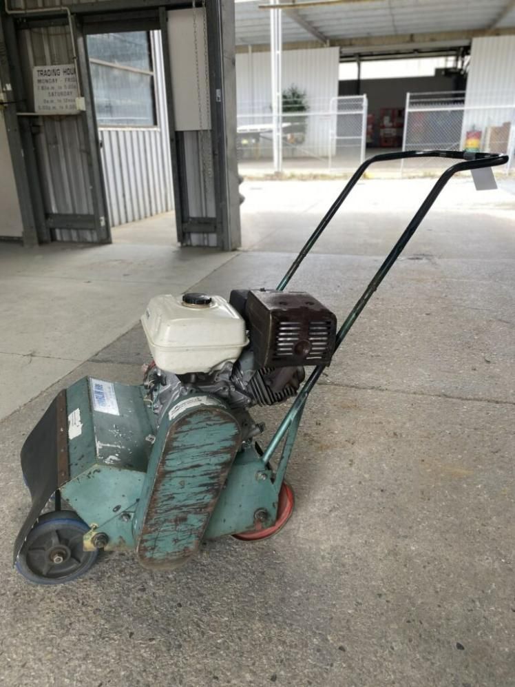 A Green Lawn Mower is Sitting on the Ground in a Parking Lot — Hamblin Hire in Albury, NSW