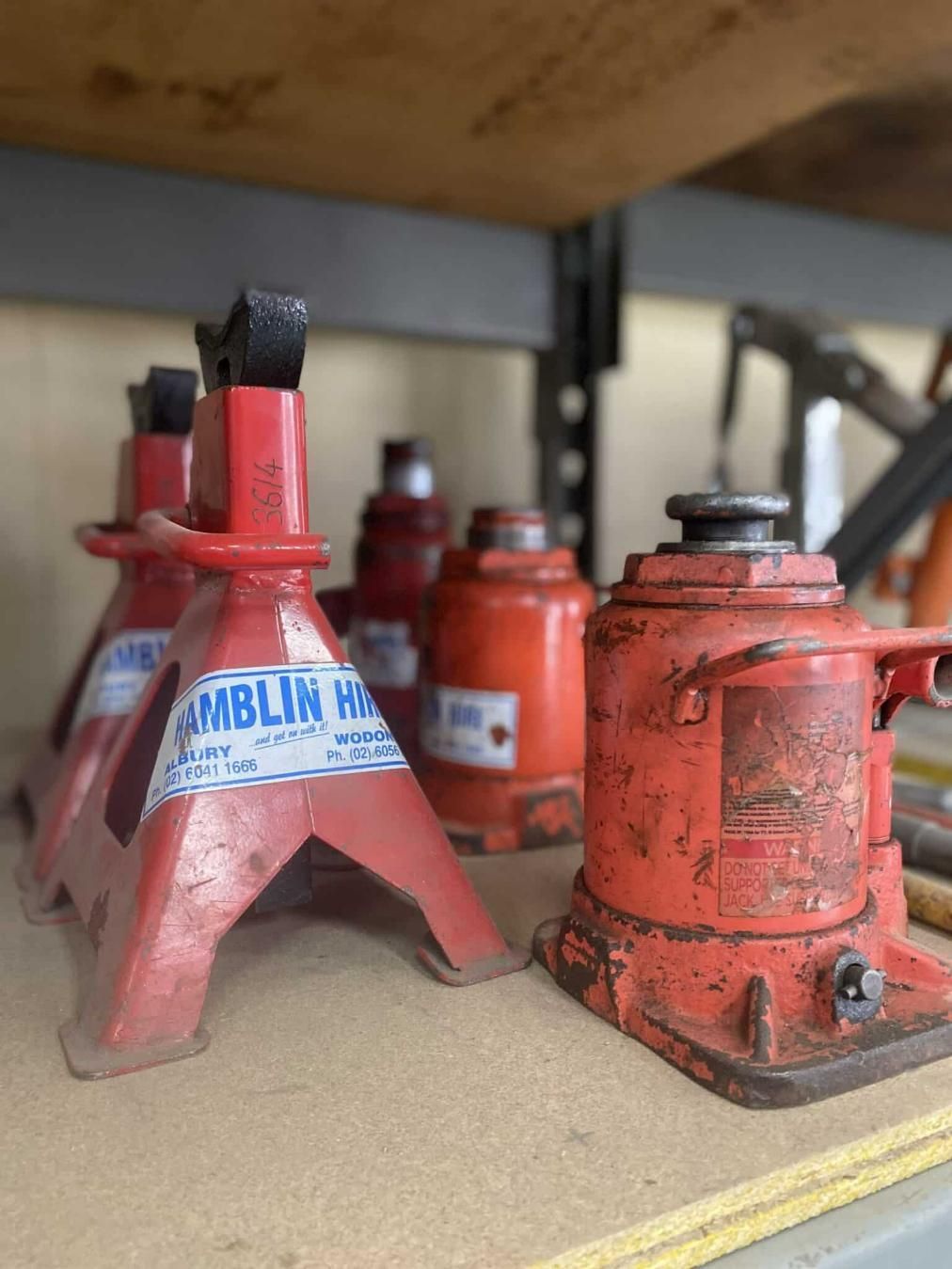 A Bunch of Red Hydraulic Jacks Are Sitting on a Table — Hamblin Hire in Albury, NSW