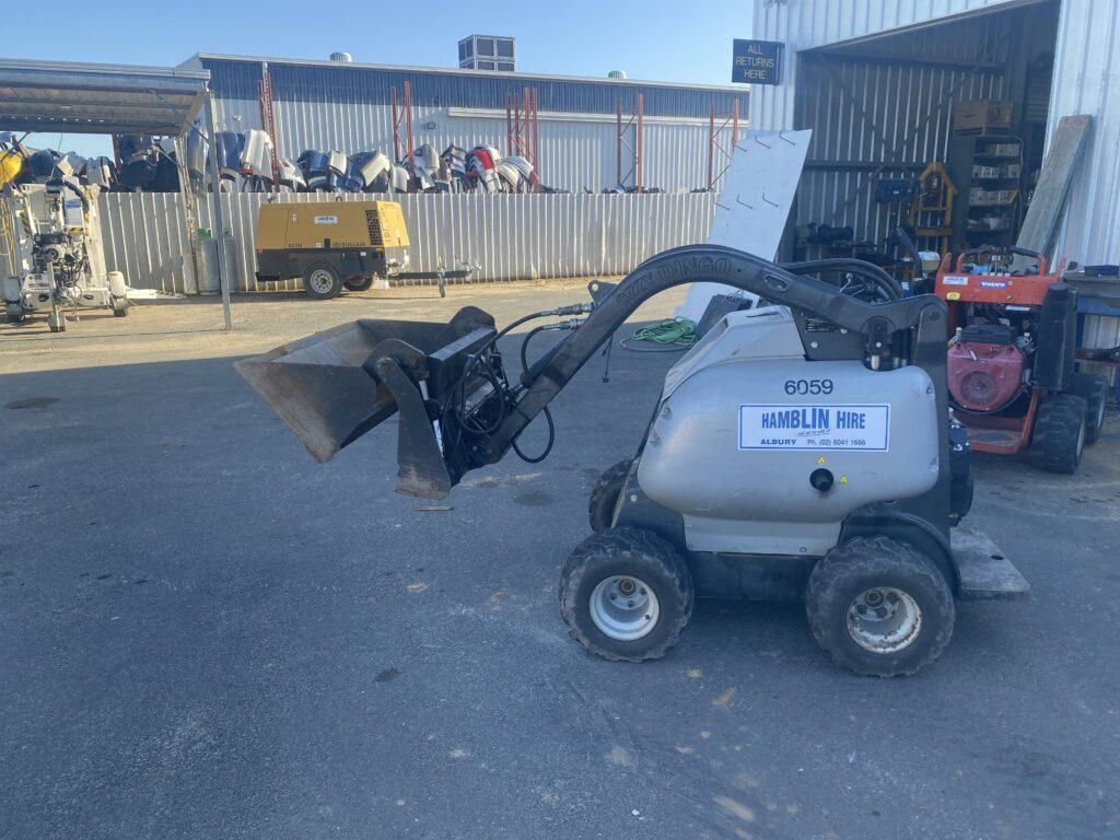 A Small Tractor With a Bucket Attached to It is Parked in a Parking Lot — Hamblin Hire in Albury, NSW