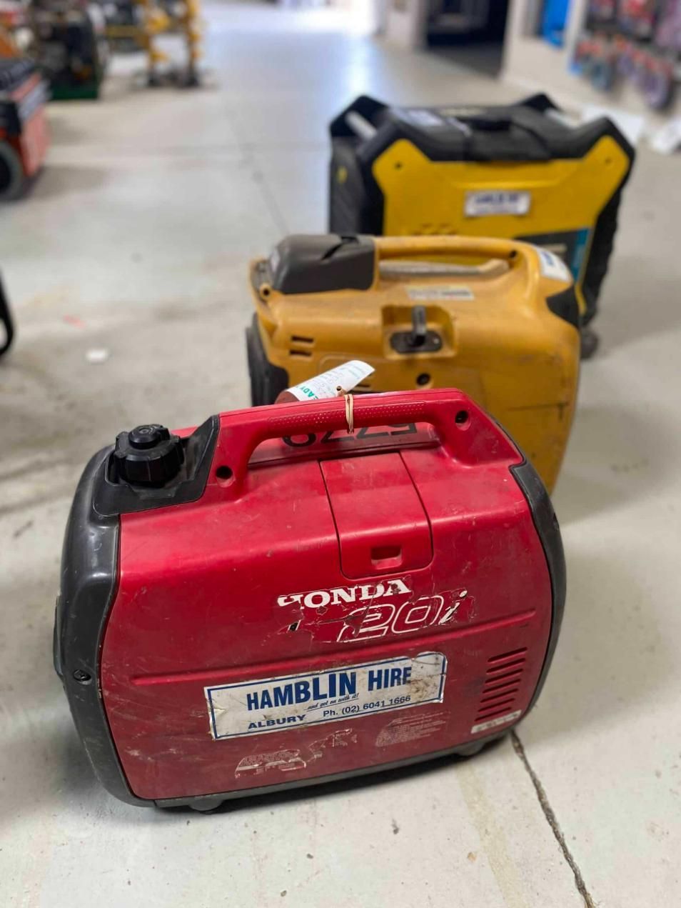 A Red Generator is Sitting Next to a Yellow Generator in a Warehouse — Hamblin Hire in Albury, NSW
