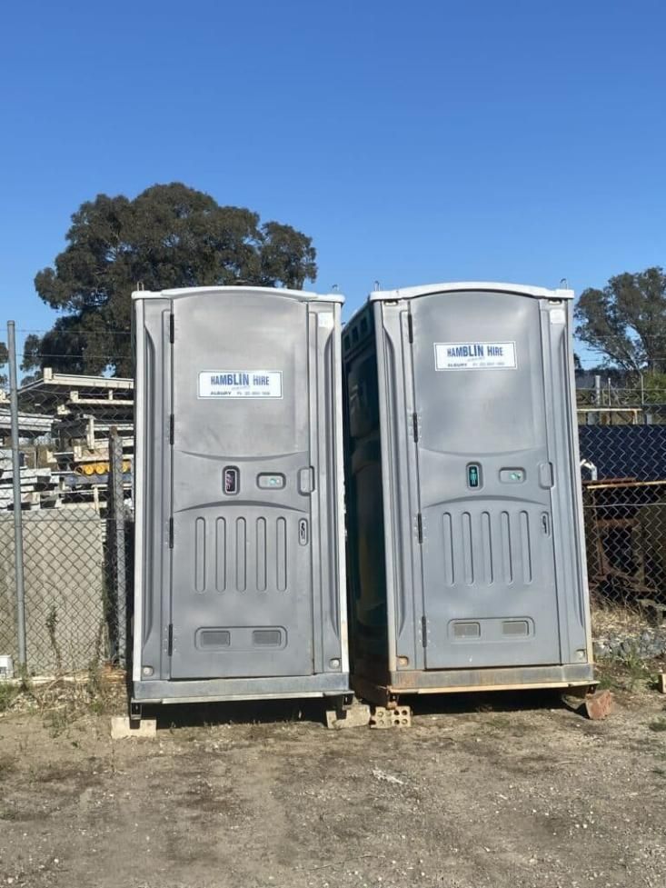 Two Portable Toilets Are Sitting Next to Each Other in a Field — Hamblin Hire in Albury, NSW
