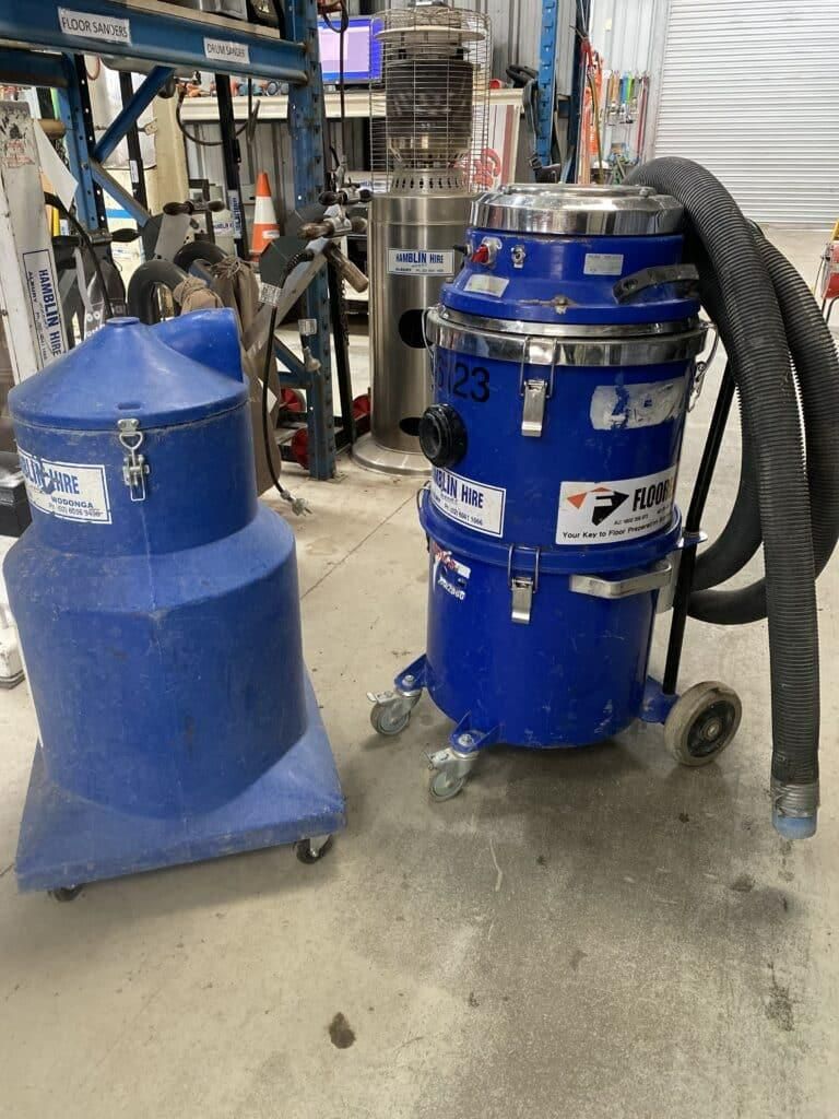 Two Blue Vacuum Cleaners Are Sitting on the Floor in a Warehouse — Hamblin Hire in Albury, NSW