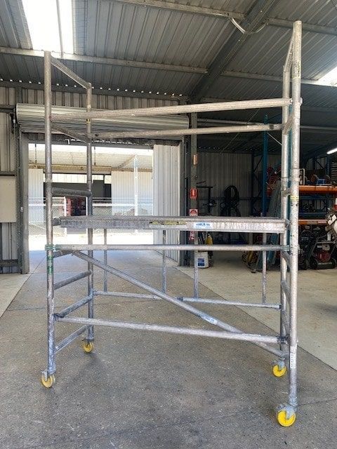 A Metal Scaffolding With Wheels is Sitting in a Warehouse — Hamblin Hire in Albury, NSW